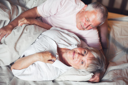 Happy elderly couple wakes up in bed in the morning