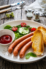 Breakfast - boiled sausages, bread and fresh vegetables served on wooden table
