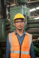 Close-up portrait of Happy asian man worker in workwear safety uniform, hard hat and vest in industrial manufacturer factory.