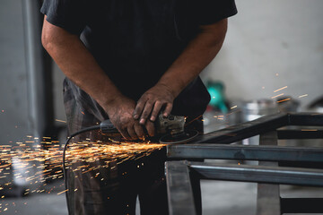 Close up on a man held an angle grinder to cut an iron with sparks
