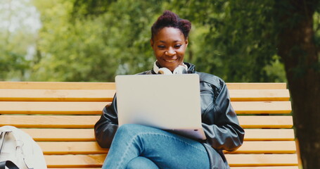 Woman freelancer with a laptop in the park uses the internet to work and study remotely with the help of communication technologies
