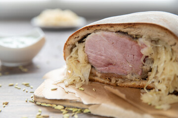 Schweinebraten im Brotteig auf Holztisch mit Fenchelsamen und Beilage grüne Sauce