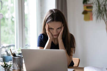 Stressed shocked young woman frustrated about problems with laptop, online app, software errors,...