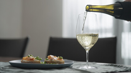 Pour white wine into glass on dinning table with copy space