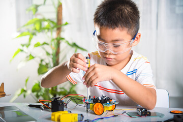 Little child tighten the nut with a screwdriver to assemble car toy, Asian kid boy assembling the...