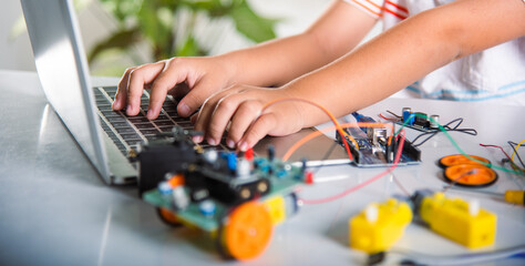 Asian kid boy learns coding and programming with laptop for Arduino robot car, Little child students typing code in computer online with car toy, STEAM education AI technology future course learning