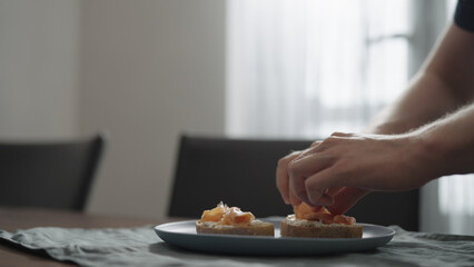 Man making bruschettas with cream cheese and smoked salmon
