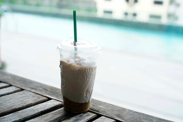 A ice coffee on the table beside a pool.