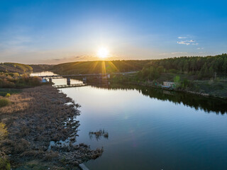 Beautiful view of the bridge across the Iset river in the city of Kamensk-Uralsky at sunset in spring. Kamensk-Uralskiy, Sverdlovsk region, Ural mountains, Russia.