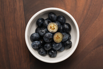 Top view of ripe blueberries in a white bowl on wood table