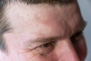 Obraz premium The upper part of the male face. A mature man with wrinkles near the eyes. Brown short hair. Close-up. Selective focus.