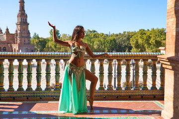 beautiful young belly dancer is posing for the camera in a photo shoot. The woman is beautiful and...