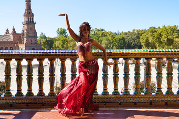 beautiful young belly dancer is posing for the camera in a photo shoot. The woman is beautiful and...
