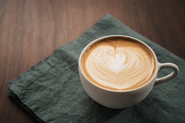 Fresh flat white with latte art in ceramic cup on wood table