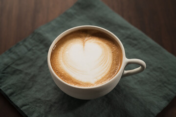 Fresh flat white with latte art in ceramic cup on wood table