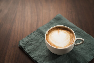 Fresh flat white with latte art in ceramic cup on wood table