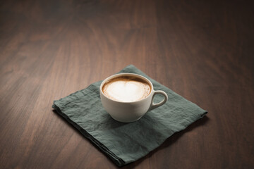 Fresh flat white with latte art in ceramic cup on wood table