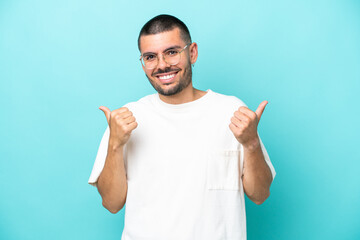 Young caucasian man isolated on blue background with thumbs up gesture and smiling