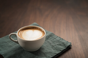 Fresh flat white with latte art in ceramic cup on wood table