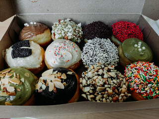 assorted donuts with chocolate frosted, pink glazed and sprinkles donuts.