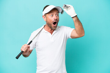 Middle age caucasian golfer player man isolated on blue background doing surprise gesture while...