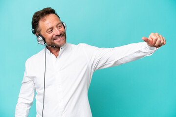 Telemarketer caucasian man working with a headset isolated on blue background giving a thumbs up gesture