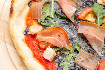 Delicious pizza with mozzarella, cuttlefish ink, served on a wooden plate . Top view.