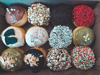 assorted donuts with chocolate frosted, pink glazed and sprinkles donuts.
