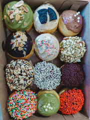 assorted donuts with chocolate frosted, pink glazed and sprinkles donuts.