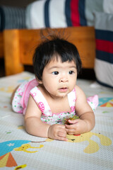 A cute caucasian infant baby is laying and playing on mattress in the living room. Baby portrait eye focus.