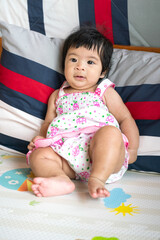 A cute caucasian infant baby is laying and playing on mattress in the living room. Baby portrait eye focus.
