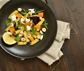 Pasta with baked pumpkin, feta, herbs and hazelnuts, top view, copy space