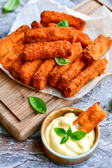 Close up of   Crispy breaded  deep fried fish fingers with breadcrumbs served  with remoulade sauce and  lemon Cod Fish Nuggets on rustic wood table background