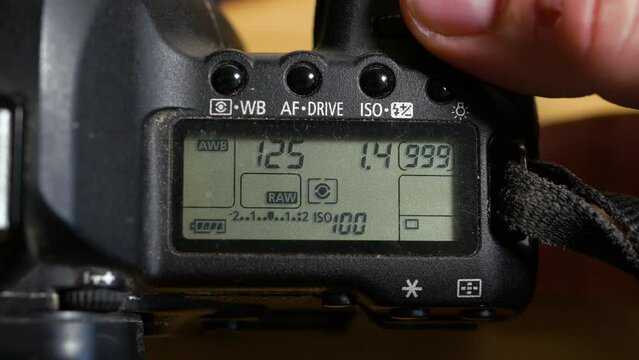 Photographer adjusting exposure modes on a SLR camera