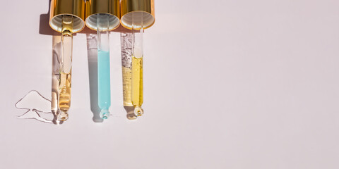 Three Pipettes with essential oil or beauty serum foe face and body skin care on pink background...