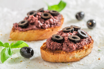 Aromatic and homemade bruschetta with black olives as snack.