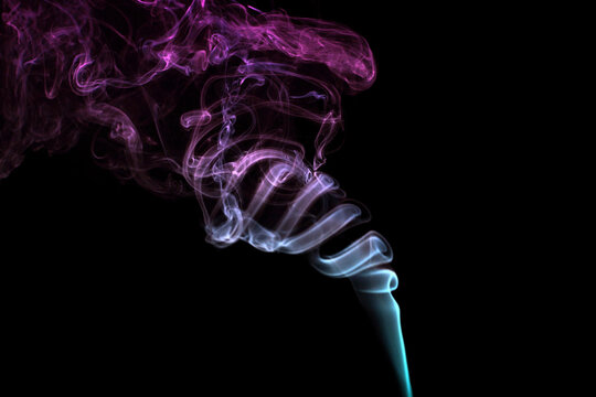 Multicolored smoke for aromatherapy relaxation on black background, beautiful swirled puffs of smoke