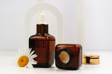 Cream and essence for moisturizing the skin of the face. Place for text. Anti aging cosmetics for women. Beautiful 
chamomile flowers and arches in background. 