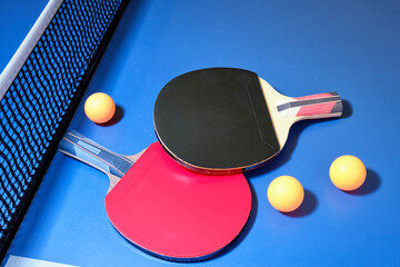 Ping pong, table tennis, racket in red and black color with orange ping pong balls on blue table.