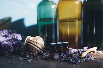 Bottle with aroma oil and lavender flowers on blue background