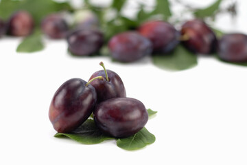 Fresh plum fruit with green leaf and cut plum slices isolated on bright background. Selective focus.