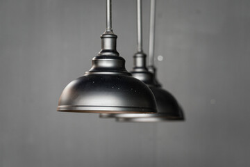 Minimal Industry style black metallic ceiling lighting lamp on gray wall background. Interior decoration object photo.