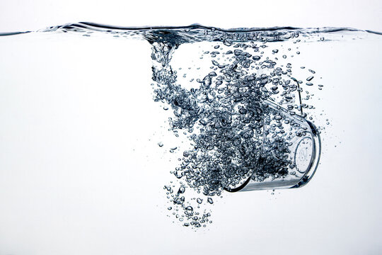 transparent glass dropped into the water on a white background