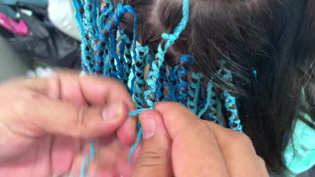 blue braids with kanekalon Zizi in the hands of a hairdresser, creativity and fashionable hairstyle concept, braiding african braids for a girl in a beauty salon
