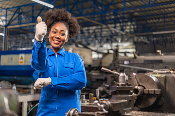 Naklejka na ściany i meble African American Young woman worker in protective uniform operating machine at factory Industrial.People working in industry.Portrait of Female Engineer looking camera at work place.