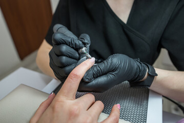 Close-up of a manicurist removing varnish from a client's nails using a router.