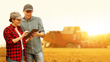 Two farmers with digital tablet on a background of combine harvester. Smart farming concept.