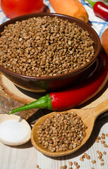 Buckwheat in a bowl, red pepper, carrots and onions on the board.