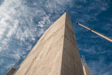 Concrete column and crane boom against the sky