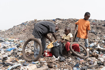 Three homeless street boys in a landfill with their daily loot of garbage to recycle and sell;...